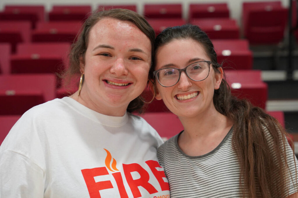 Two students smiling in front of bleachers