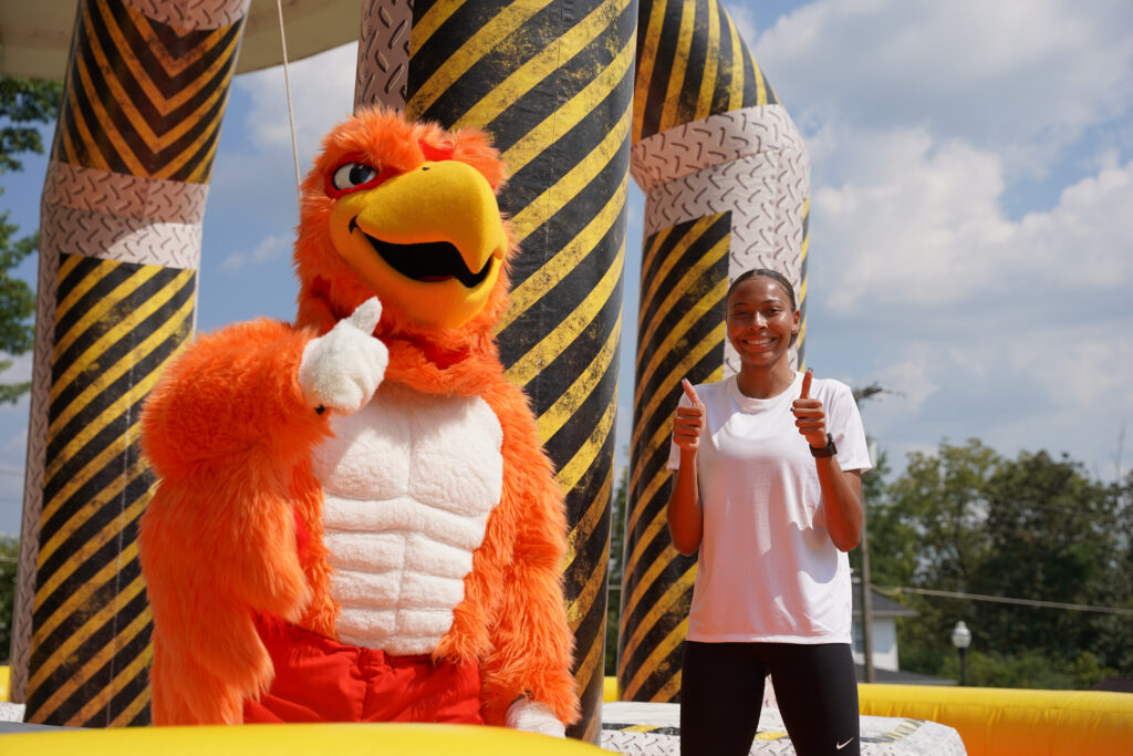 Firehawk mascot and student giving thumbs up