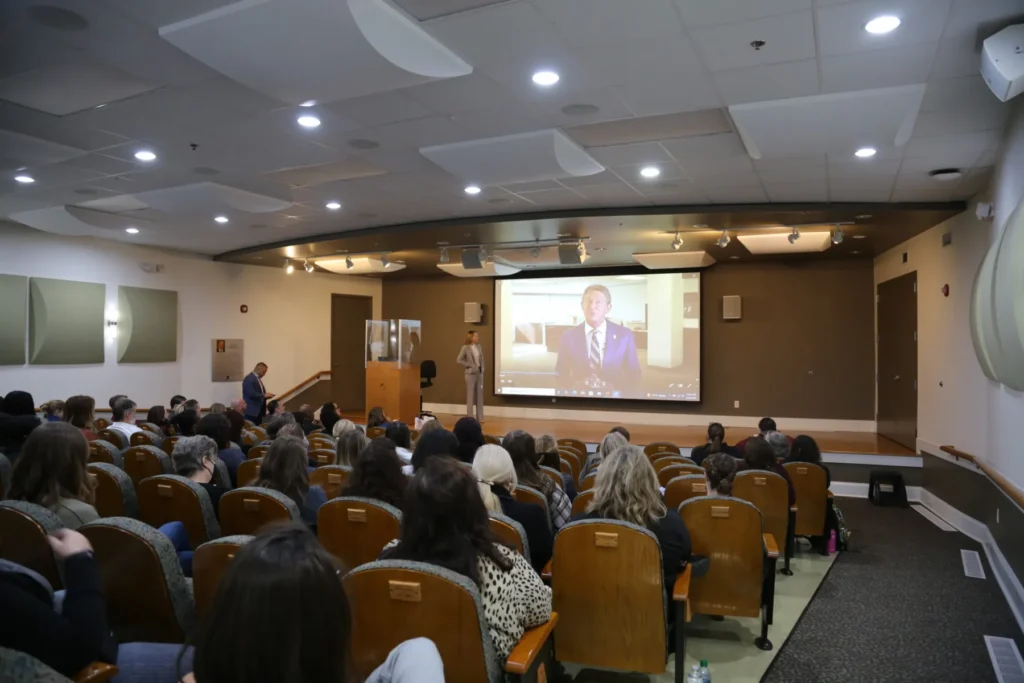 A lecture hall of people watching a video