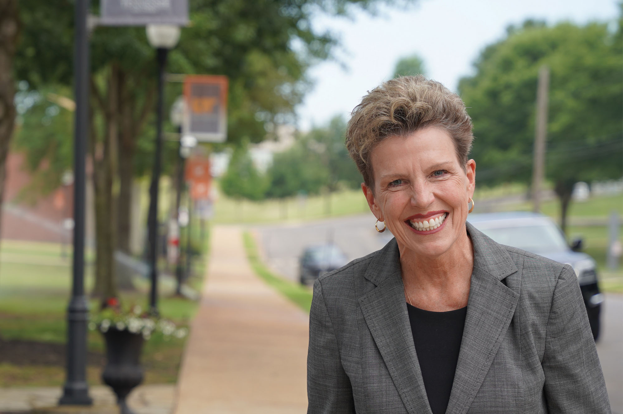 Chancellor Martin standing outside on a sidewalk with trees out of focus behind her.