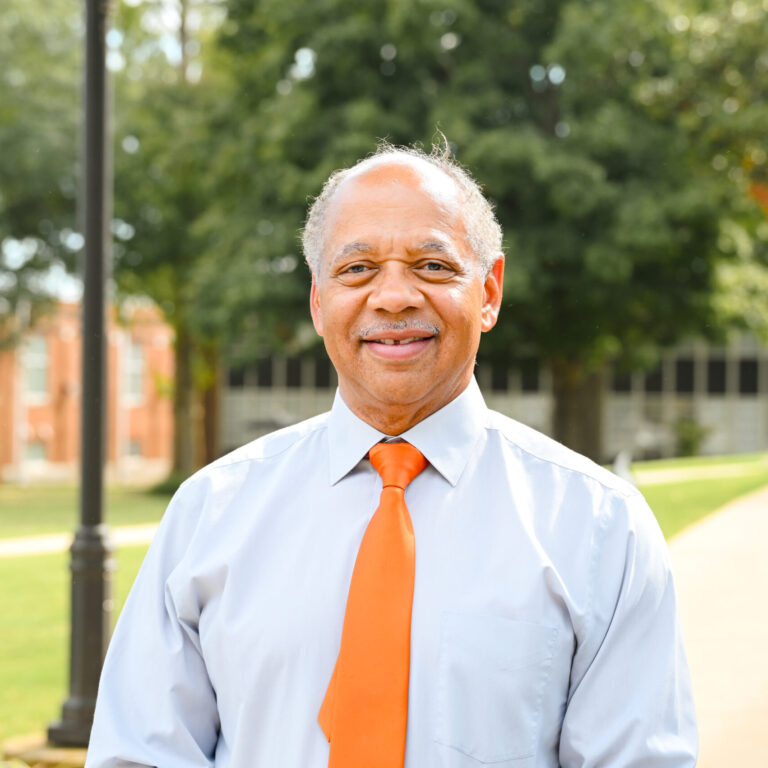 Scott Gaines, professor, posing on the campus green smiling for a headshot