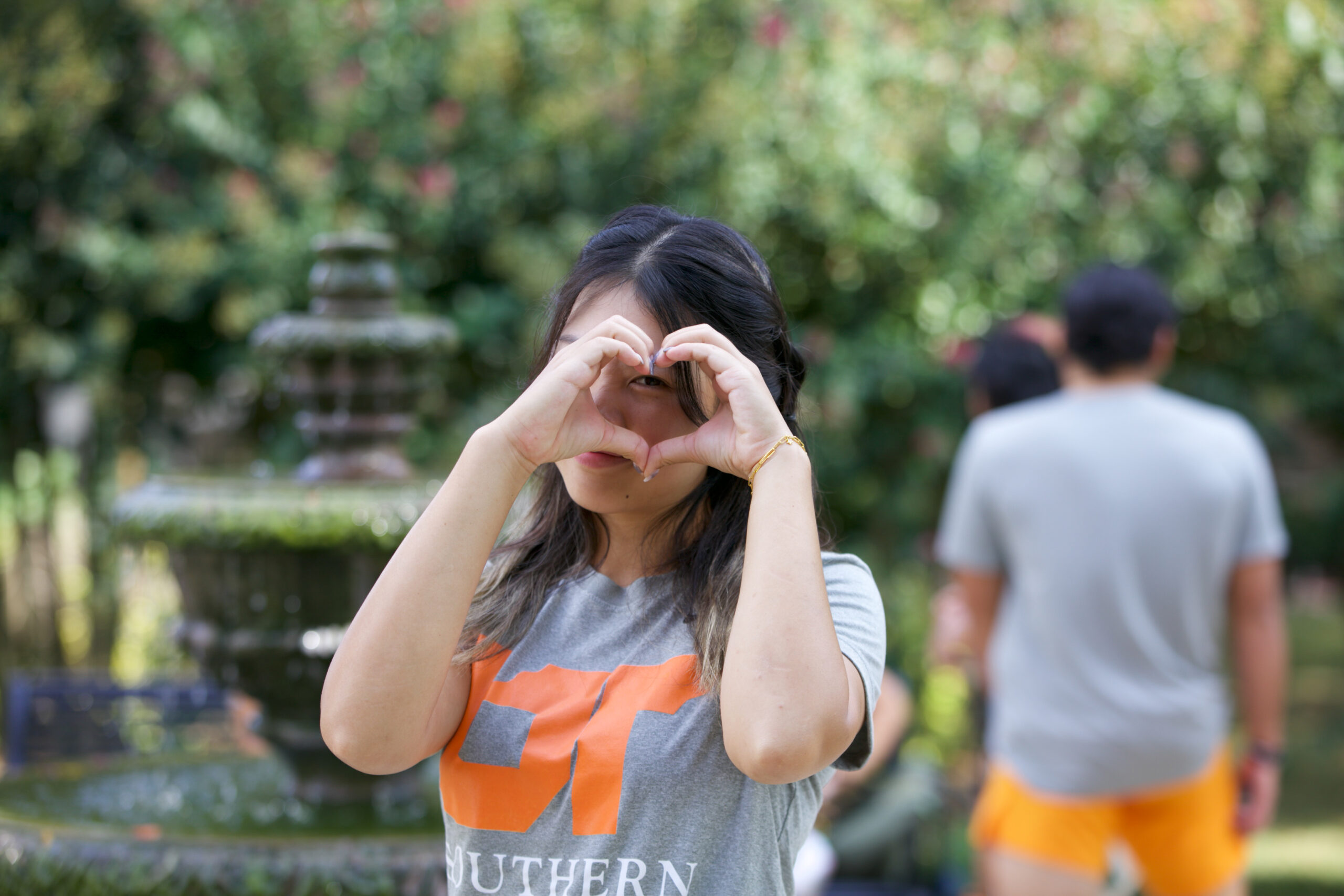 A girl in UT Southern shirt making a heart with her hands