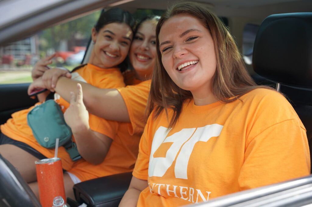 Three students in UT southern shirts pictured in a car, smiling