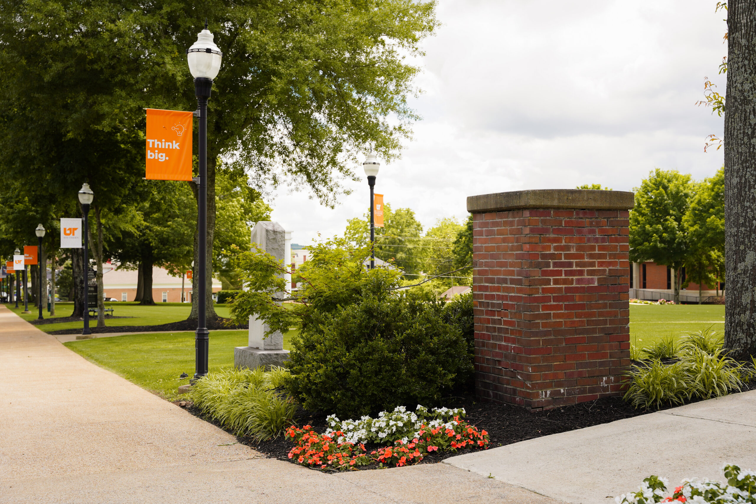 Landscape photo of the campus with a pole light and "think big" banner.